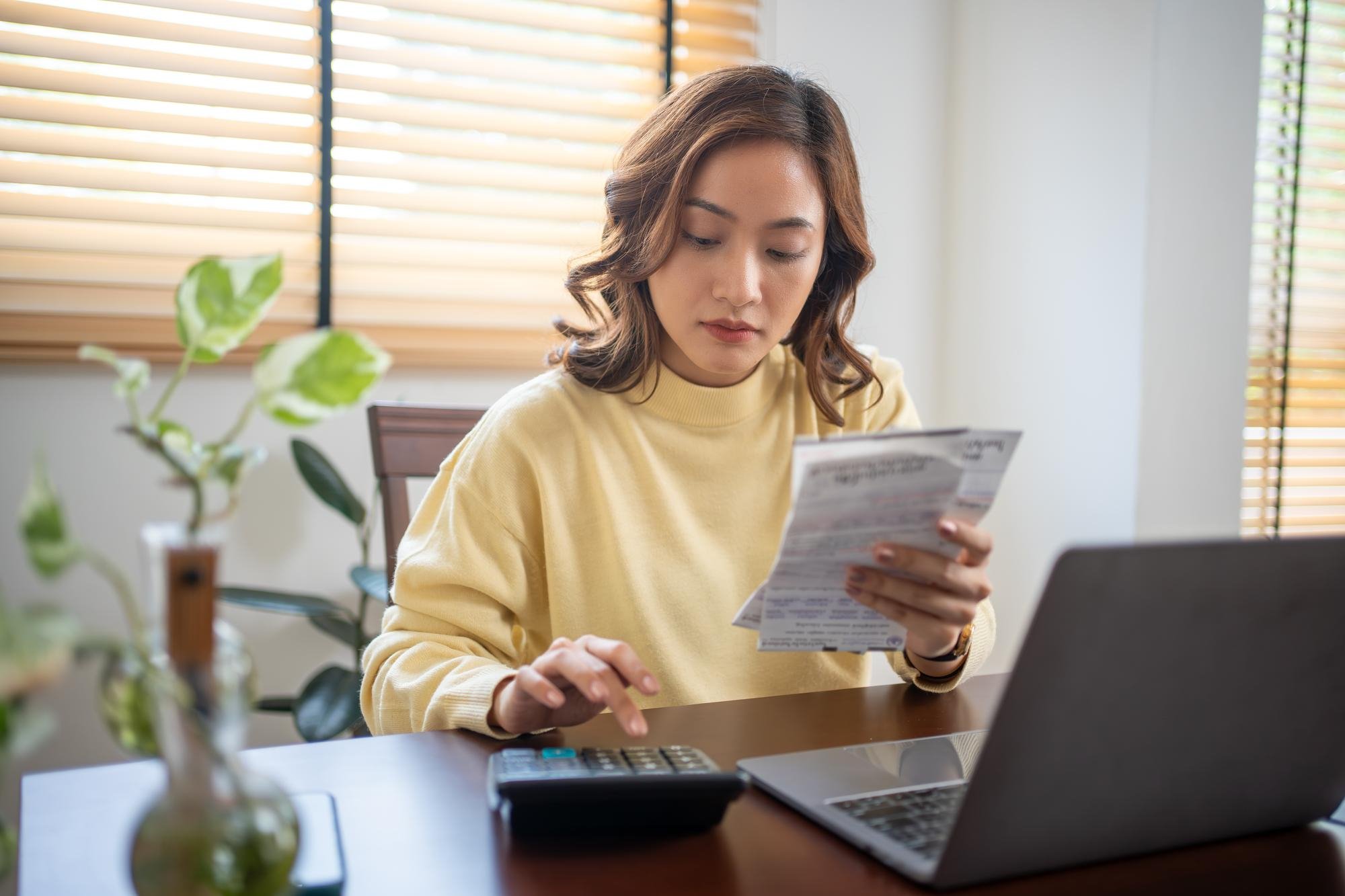 Woman reviewing credit documents with a calculator